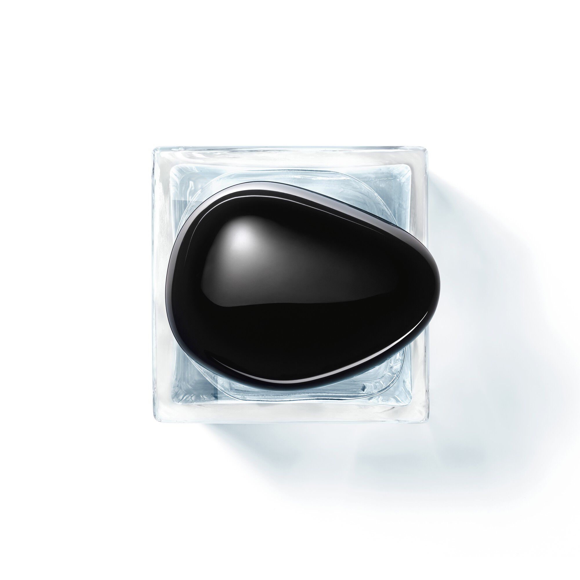 Flacon de parfum design elegant avec capuchon noir, pose sur un socle transparent.