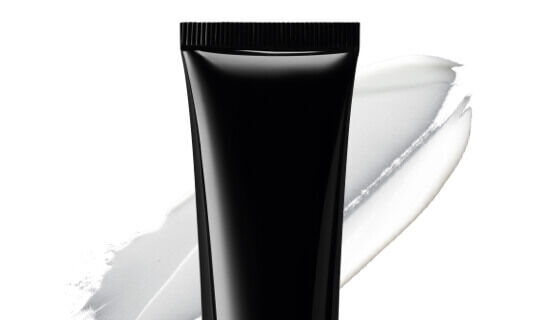 Tube noir de produit cosmetique sur fond blanc, avec une trainee de creme blanche a cote.