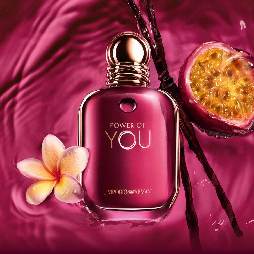 ARMANI POWER OF YOU perfume bottle surrounded by passion fruit, frangipani flowers, and vanilla beans on a radiant ruby background.