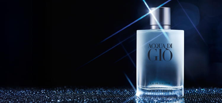 A black and white image featuring a man beside the ocean, gazing intently at the camera, with a bottle of Acqua di Gio perfume displayed prominently on the side.