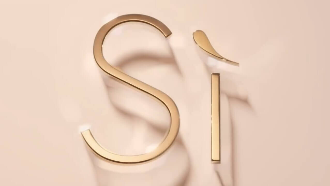 A close-up of the stylized text "Si" in gold against a soft beige background, with smooth, flowing textures surrounding it.