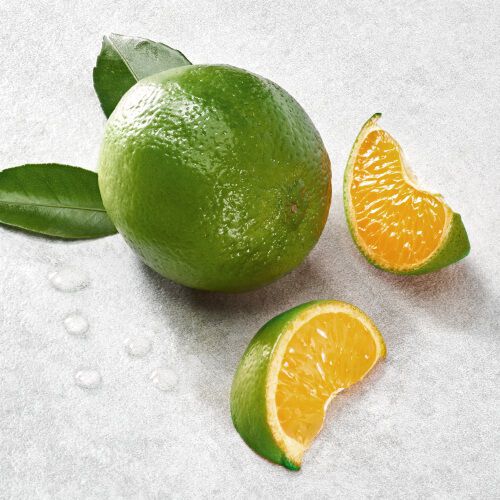 Eine grune Orange mit zwei einzelnen, saftigen Segmenten und frischen Blattern auf einem hellen Hintergrund.