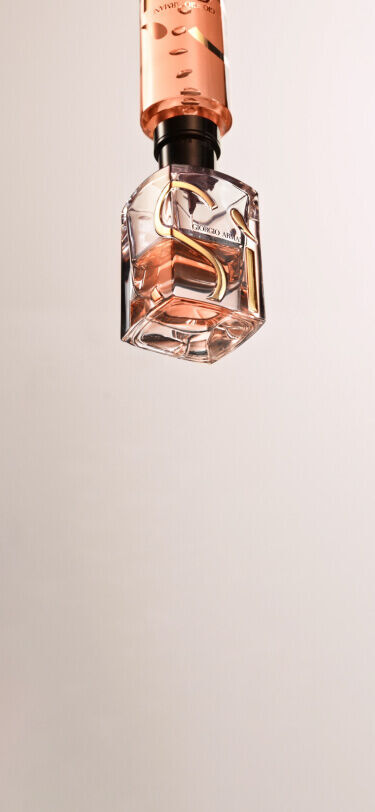 Ein eleganter Flakon eines Parfums, der schwebend in der Luft dargestellt wird. Der Flakon hat eine klare Unterseite und einen rosa Deckel.