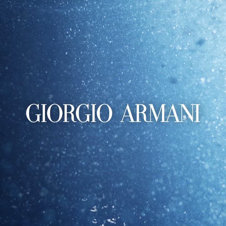 The image features the text "Giorgio Armani" prominently displayed against a textured blue background with soft bubbles or water droplets.
