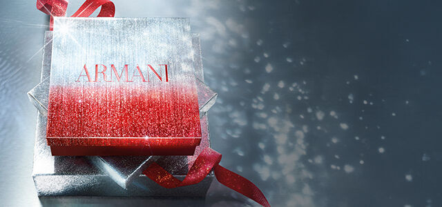 Boite cadeau Armani scintillante rouge et argent avec un ruban rouge, sur un fond scintillant.