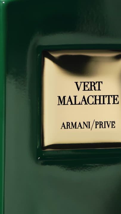 A sleek green "Armani/Prive Vert Malachite" fragrance bottle with a rounded cap. Ethereal green plant silhouettes, including a calla lily, gently overlay the bottle, emphasizing its fresh, natural essence.