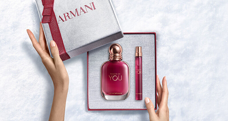 Flacon de parfum Giorgio Armani « Si » a cote d'un grand coffret cadeau Armani rose texture.