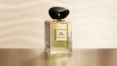 Parfumflakon Armani/Prive „The Yulong“ auf Blattern uber gewelltem Wasser.