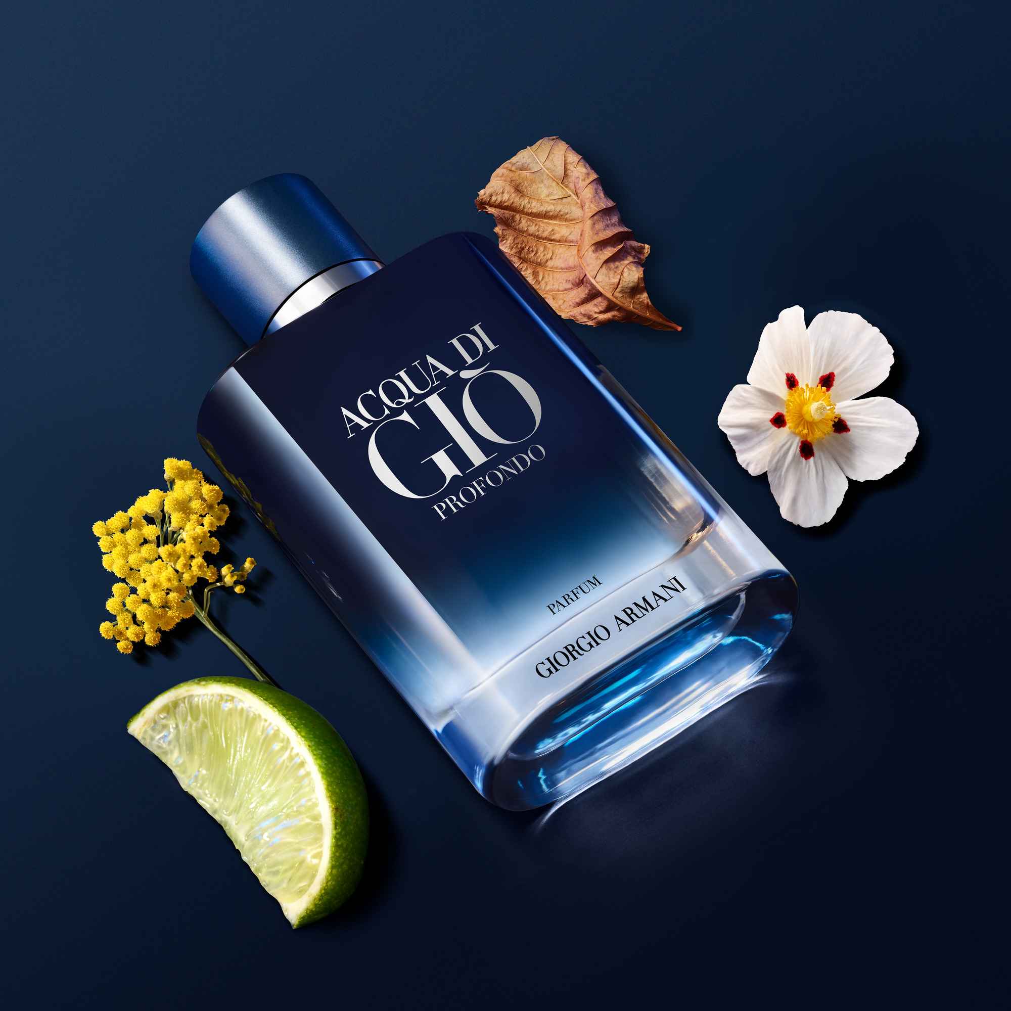 Flasche des Parfums 'Acqua di Giò Profondo' von Giorgio Armani, umgeben von Blumen, Blättern und einer Limette.