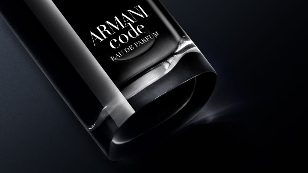 A close-up of a black glass bottle of Armani Code Eau de Parfum against a dark background, showcasing its sleek design.